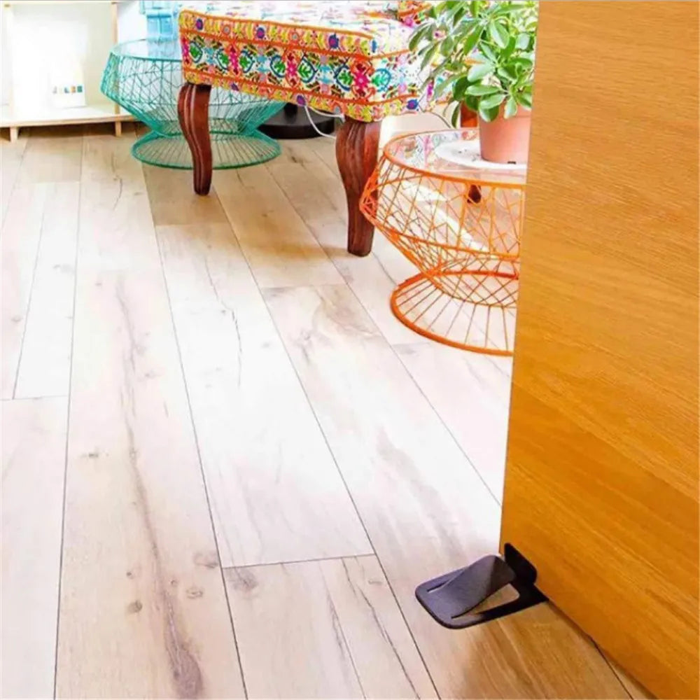 Tope de puerta pegado al suelo de madera sujetando una puerta abierta
